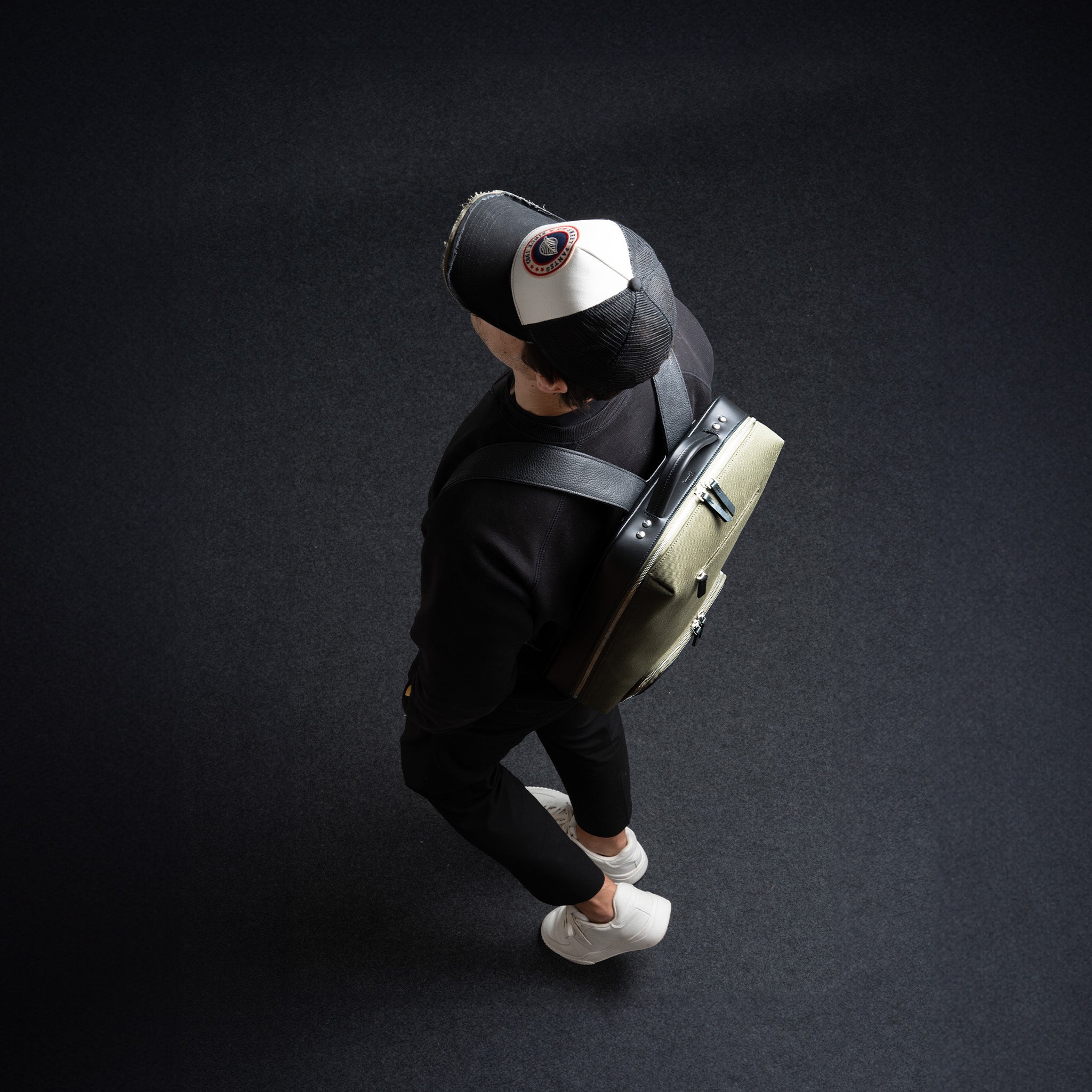 Dos d’un homme tenant un sac à dos en cuir pour ordinateur, idéal pour transporter son laptop avec élégance.