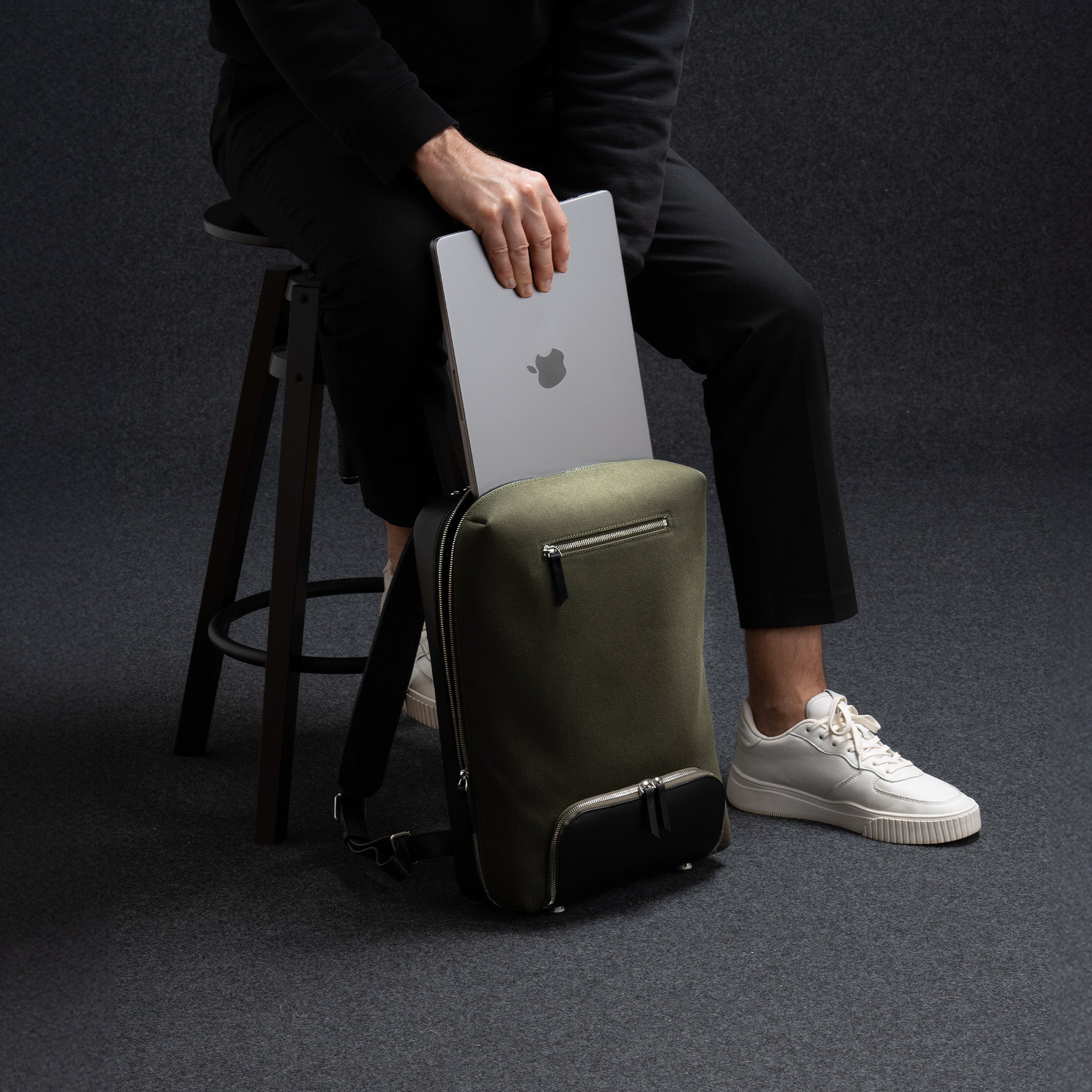 Sac à dos tendance homme en cuir noir et toile kaki, avec un rangement trousse de toilette et ordinateur.