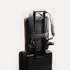 Sac à dos homme en cuir fixé à une valise cabine pour voyage.