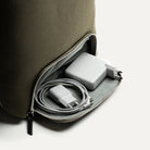 Rangement technique du sac à dos en cuir avec chargeur et câbles.