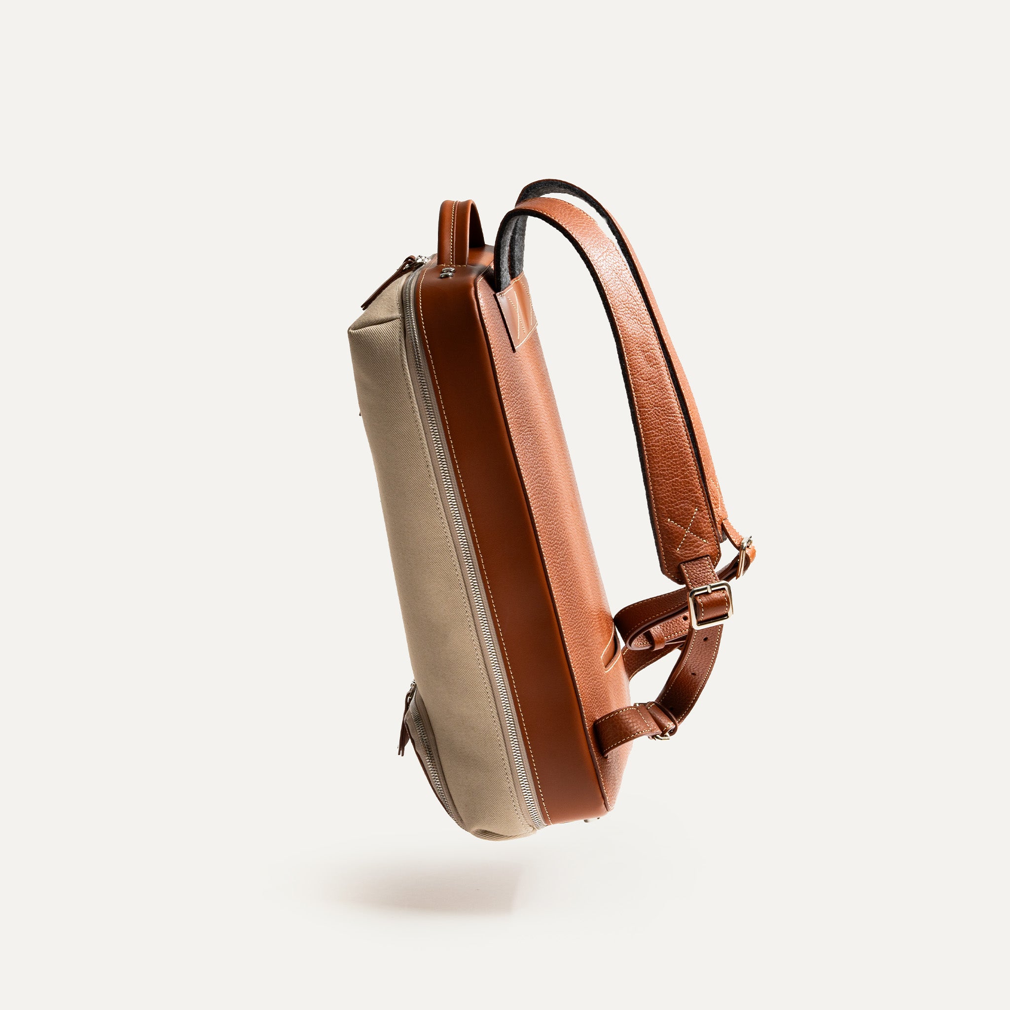 Côté du sac à dos ordinateur homme en toile beige et cuir marron, silhouette fine.