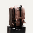Sac à dos en cuir grainé marron pour ordinateur accroché à une valise