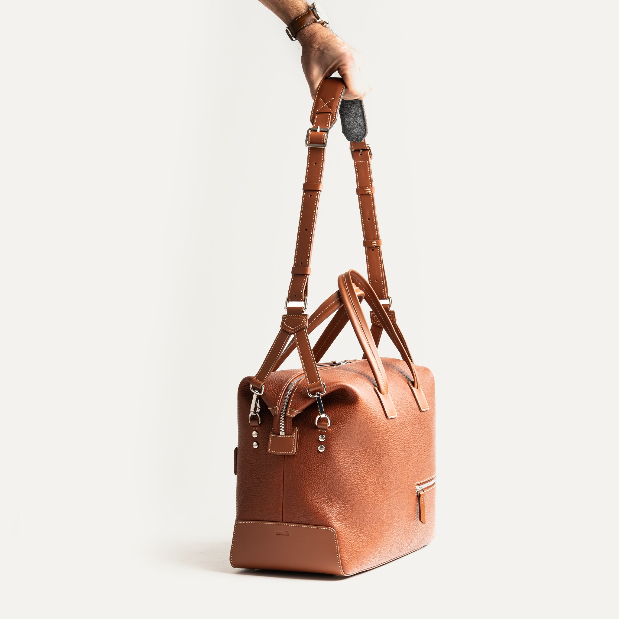 Sac weekender en cuir marron avec bandoulière ajustable, pratique pour les déplacements professionnels.