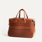 Sac weekender en cuir marron avec passant trolley arrière intégré, idéal pour déplacements en avion.