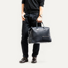 Sac de voyage homme porté par un homme à la main.