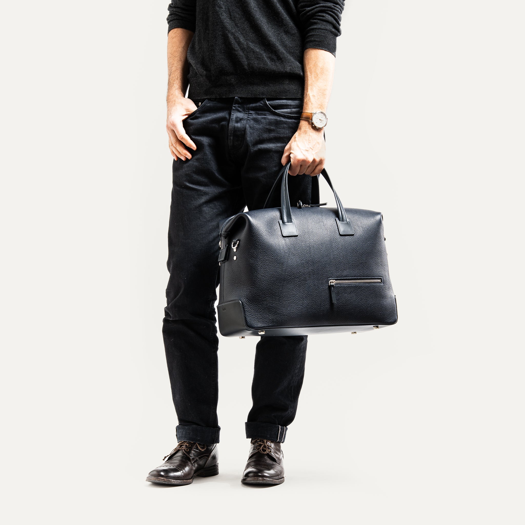 Sac de voyage homme porté par un homme à la main.