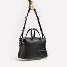 Sac de voyage pour homme en cuir noir porté à l'épaule avec bandoulière réglable, modèle 48 heures.