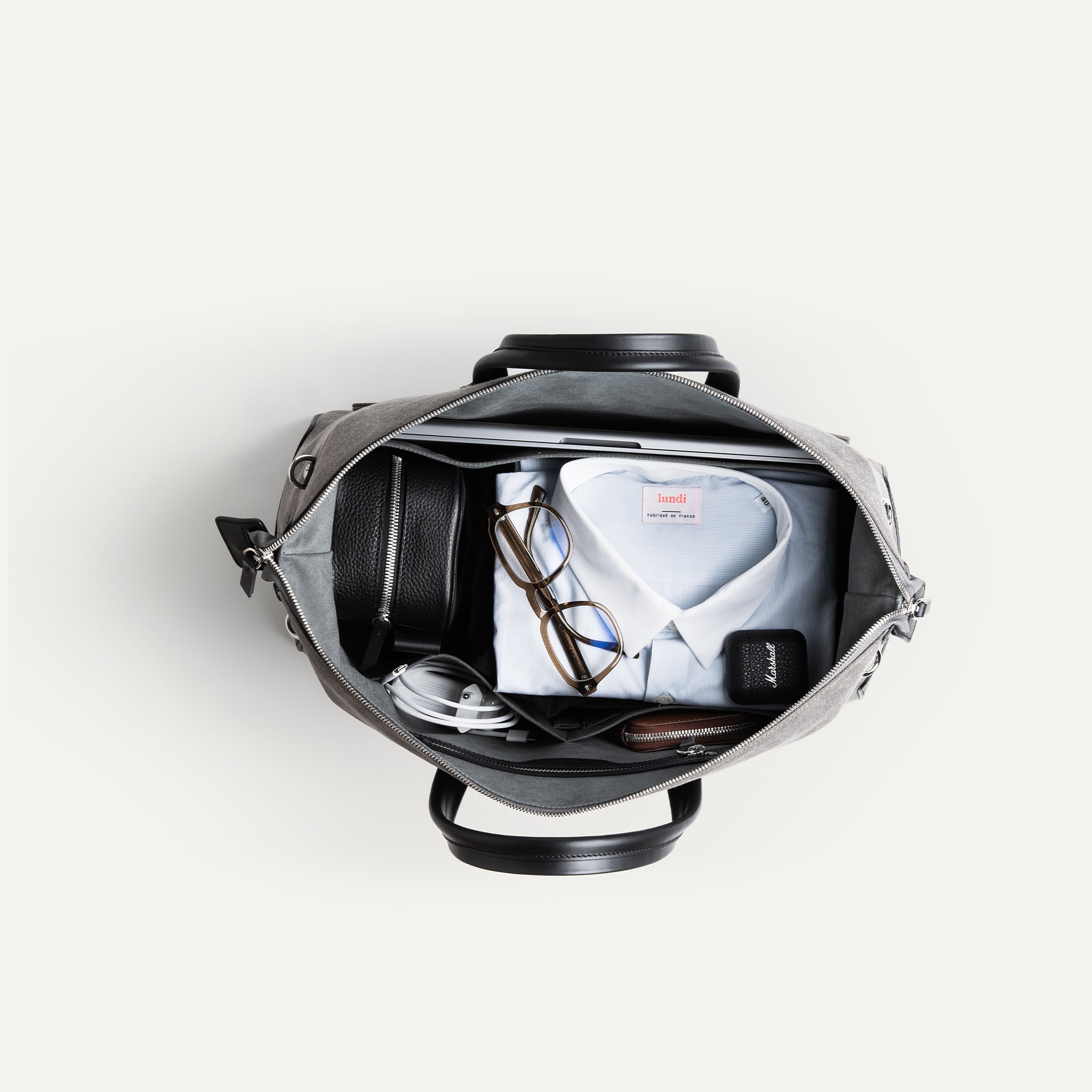 Sac weekender en toile et cuir, intérieur Alcantara gris avec compartiments pour ordinateur, chaussures et accessoires.