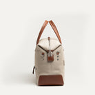 Sac de voyage pour homme en toile beige et cuir cognac, passant trolley intégré pour valise cabine.