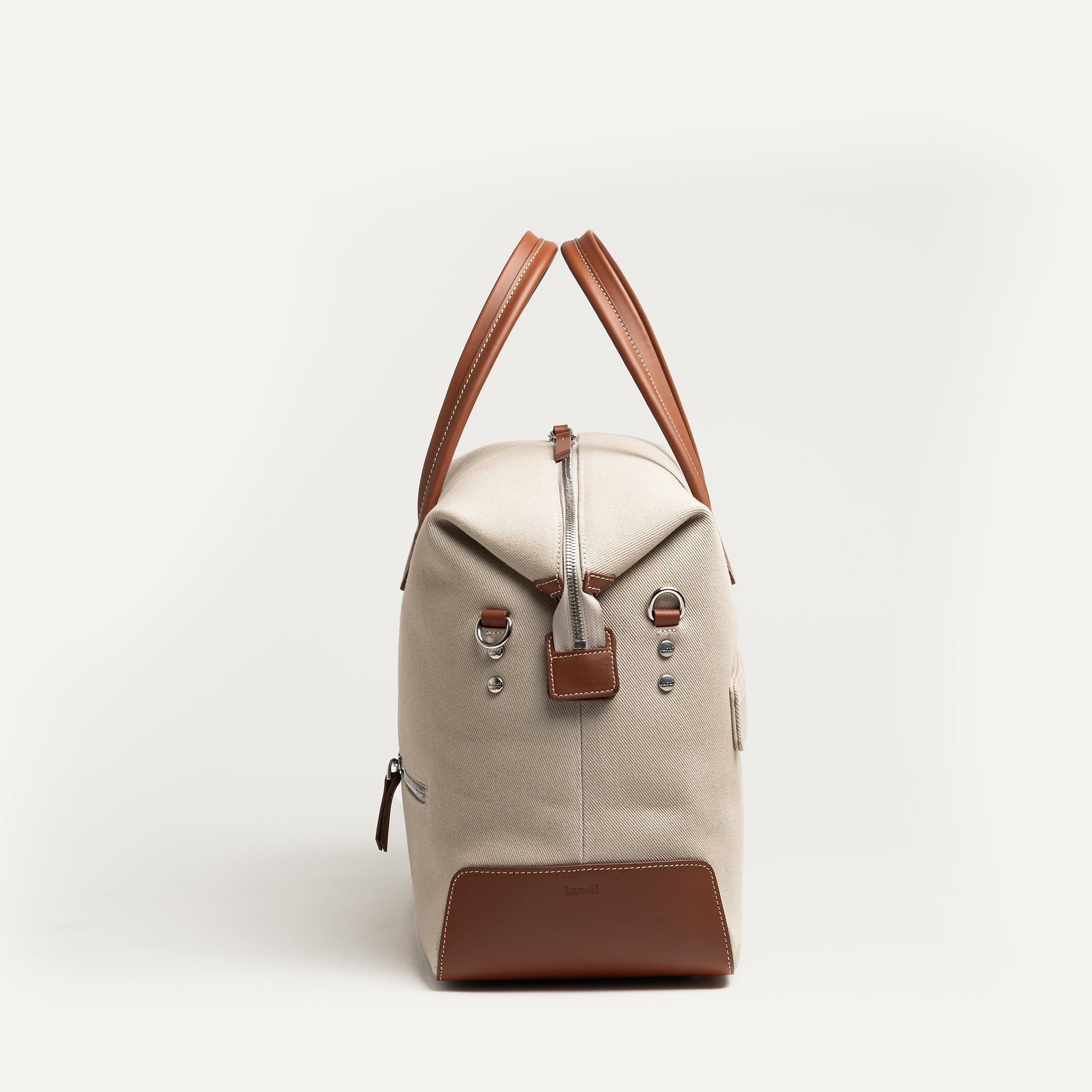 Sac de voyage pour homme en toile beige et cuir cognac, passant trolley intégré pour valise cabine.