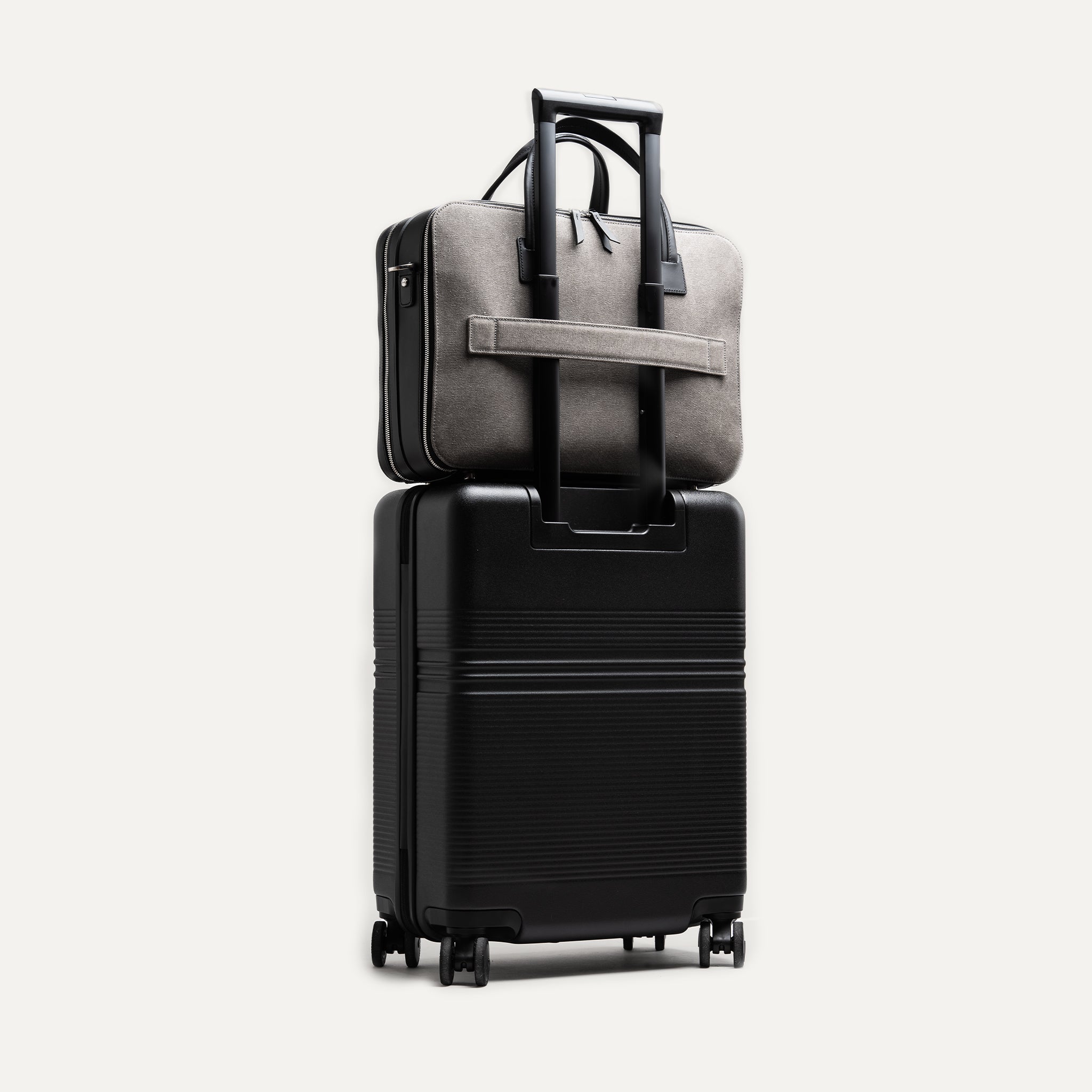 Briefcase CONALLY en toile de coton déperlante gris et cuir tannage végétal, équipé d’un passant trolley pour valise.