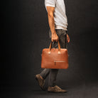 Sac à main homme camel porté avec tenue casual chic, parfait pour un style professionnel.