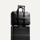 Sac homme travail TILIO II posé sur une valise avec sangle valise intégrée et aimantée pour voyager léger.