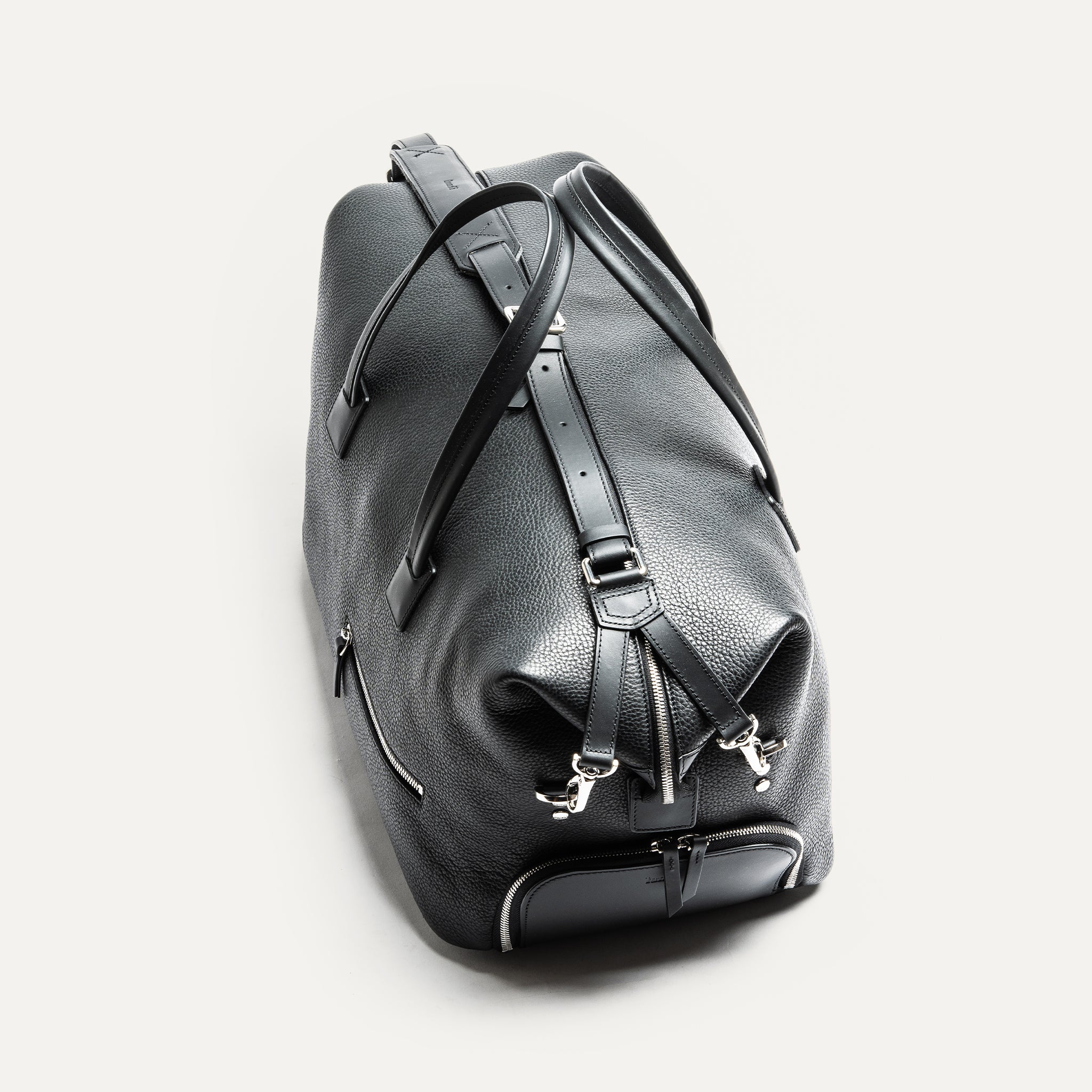 Ce sac en cuir noir est idéal pour les voyages courts. Il offre un espace de rangement pour vêtements et une poche pour ordinateur portable. Les poches extérieures sont parfaites pour ranger chaussures et accessoires.