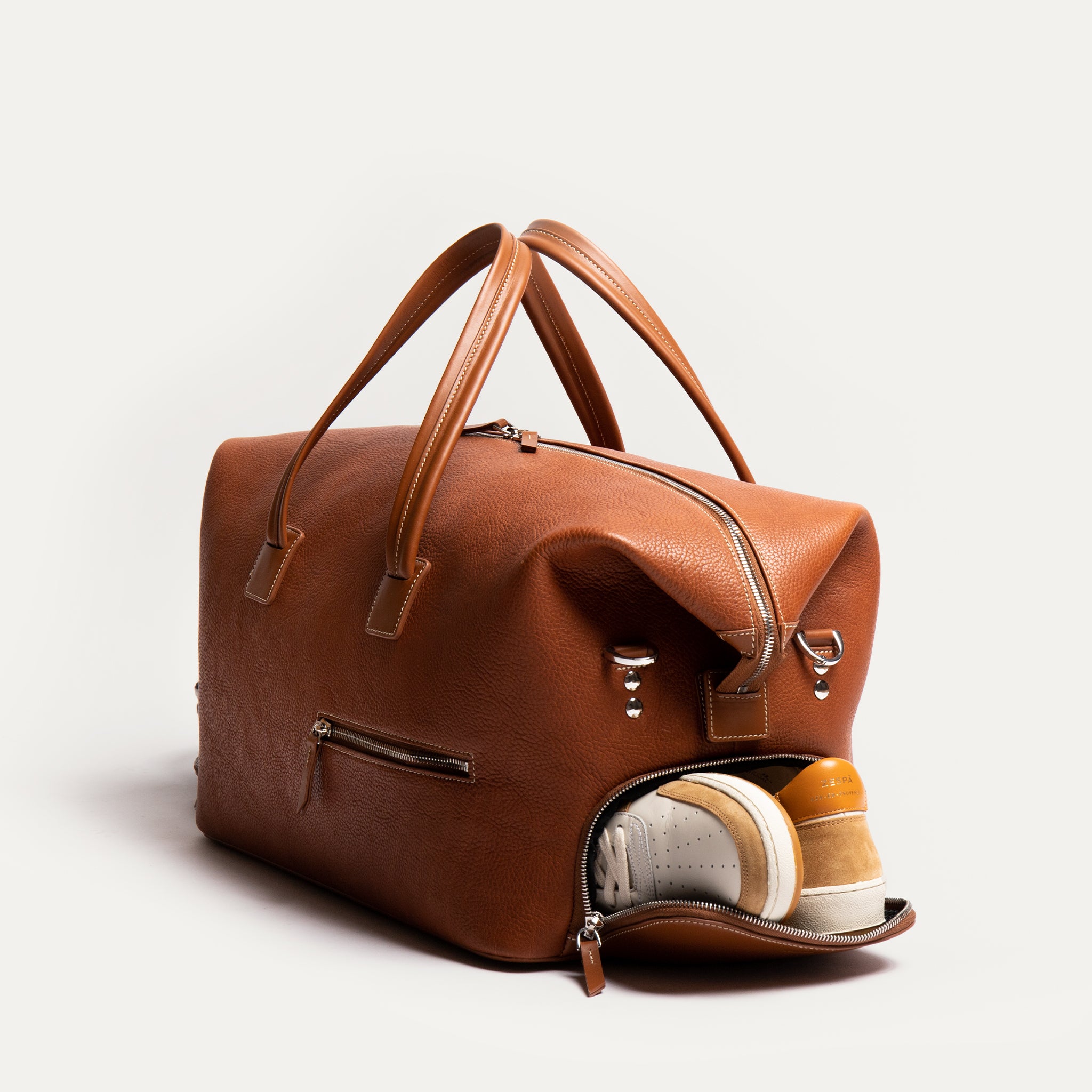 Sac de voyage en cuir cognac doté de poches multiples, dont un compartiment pour chaussures.