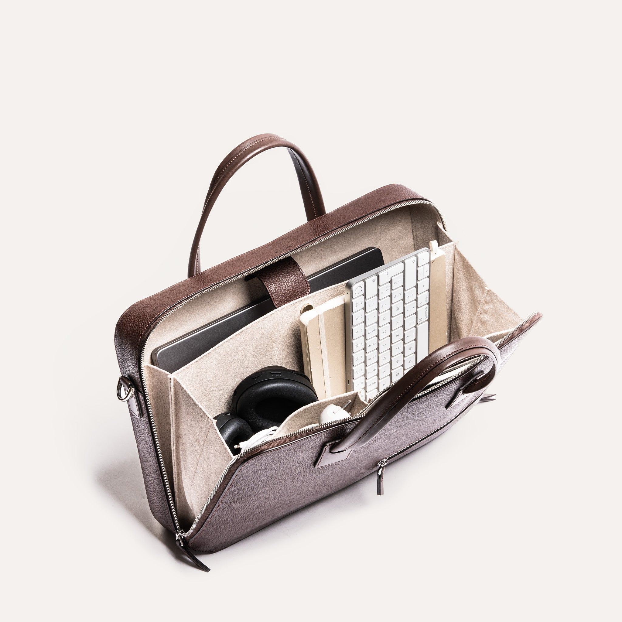 Vue plongeante sur un porte document spacieux, contenant clavier, carnet et casque, pensé pour un usage fonctionnel.