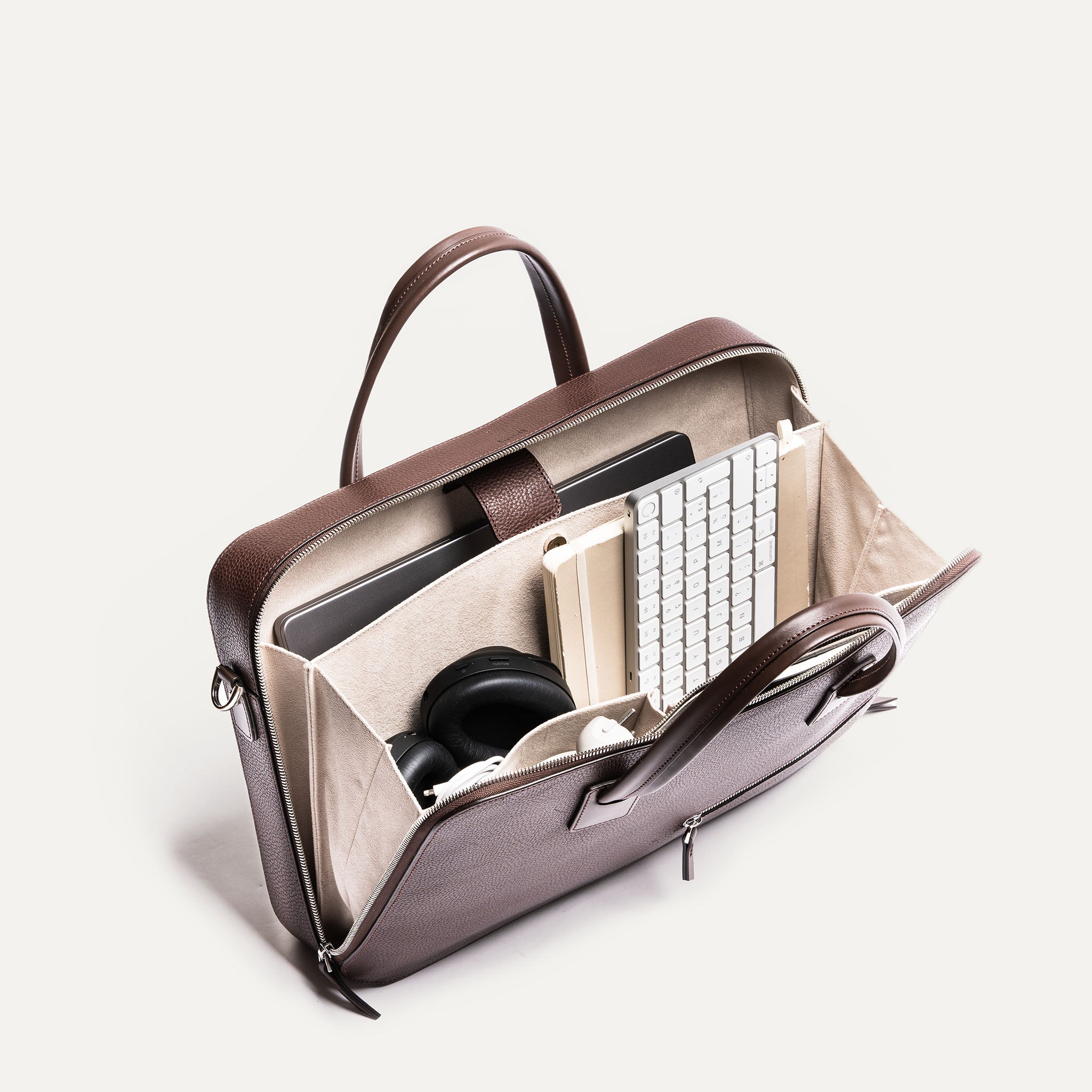 Vue plongeante sur un porte document spacieux, contenant clavier, carnet et casque, pensé pour un usage fonctionnel.