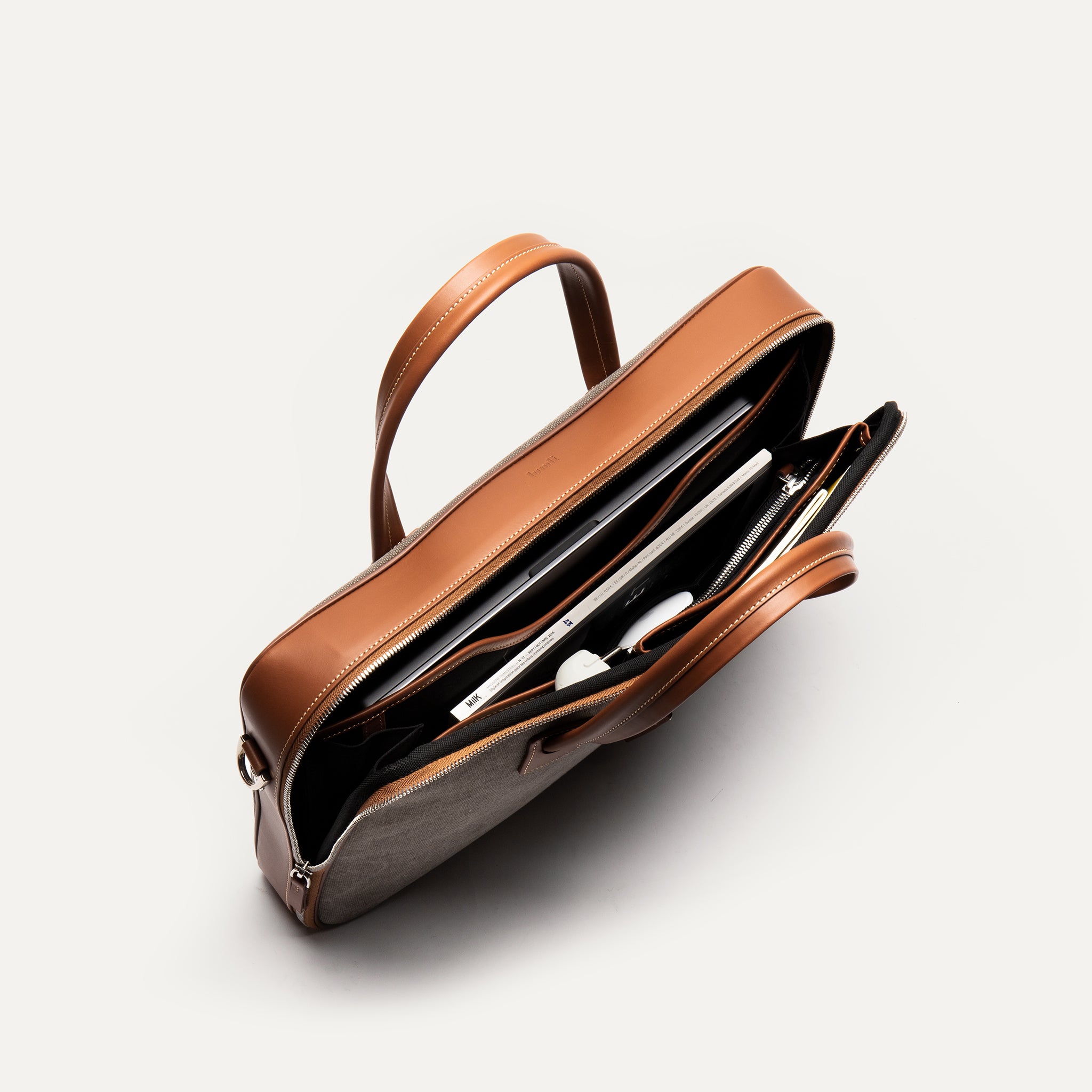 Sac à bandoulière homme en cuir et toile cognac avec des compartiments séparés.