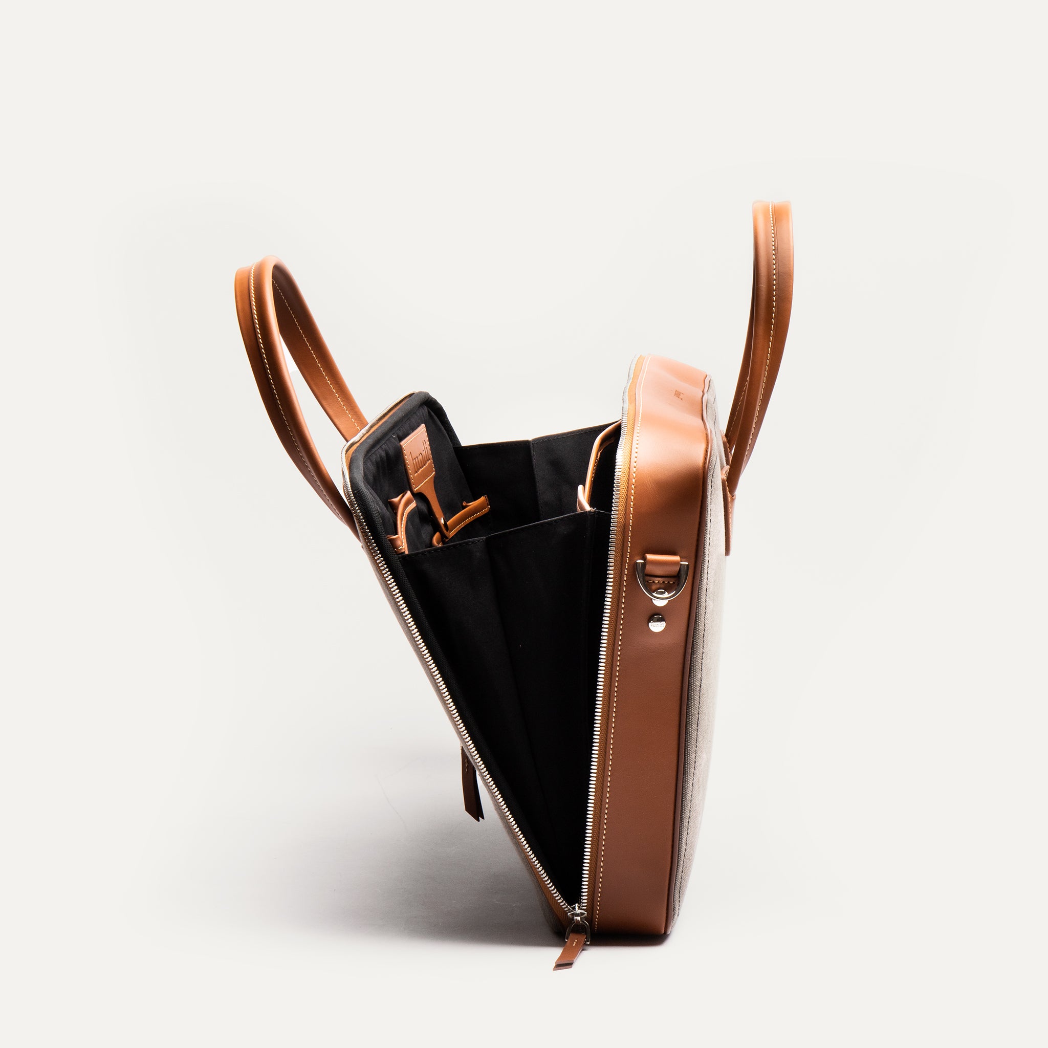 Porte document en cuir et toile ouvert présentant un espace dédié pour l'ordinateur, ses documents et ses accessoires.