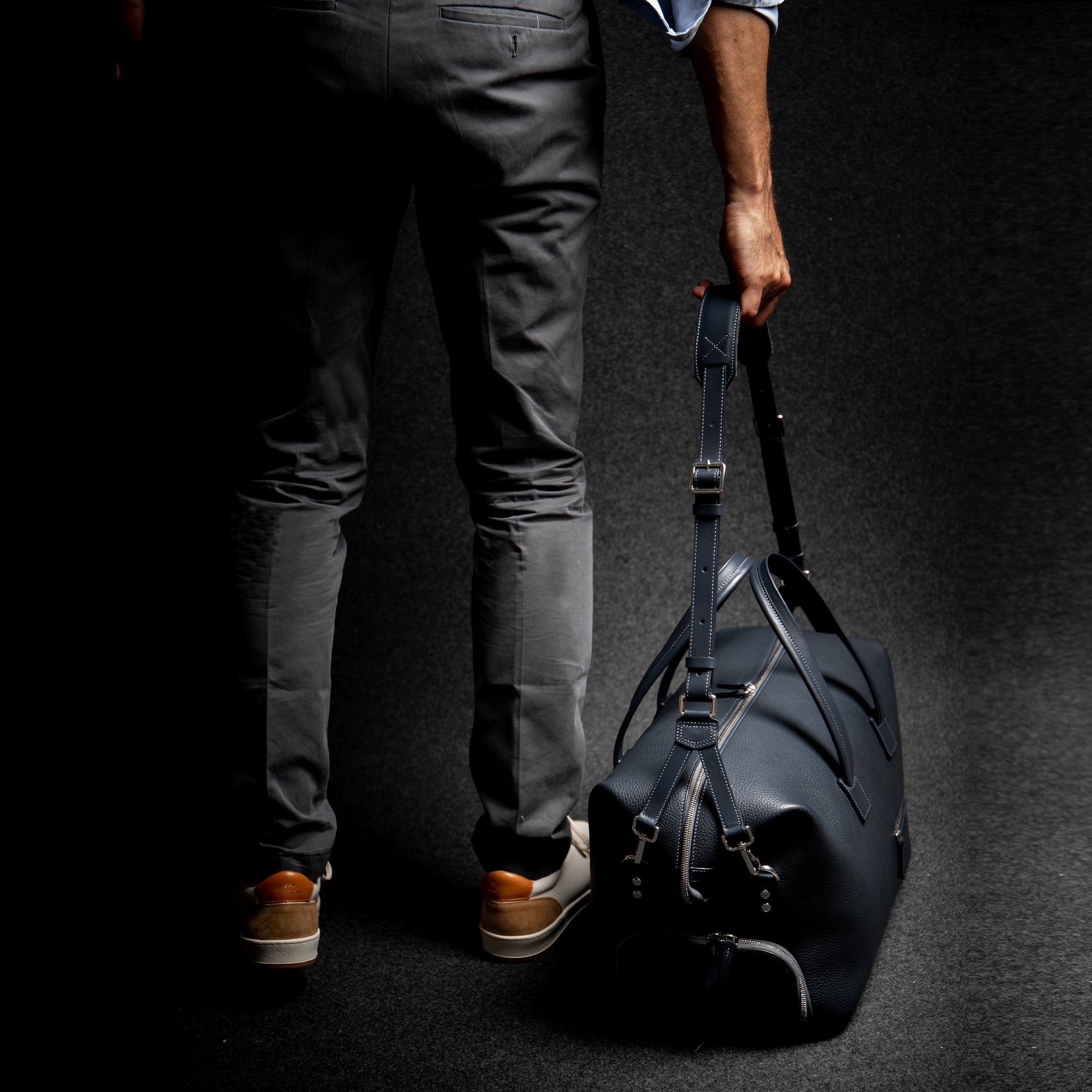 Sac de voyage pour homme en cuir marine portée à l'aide d'une bandoulière assorti et ajustable.