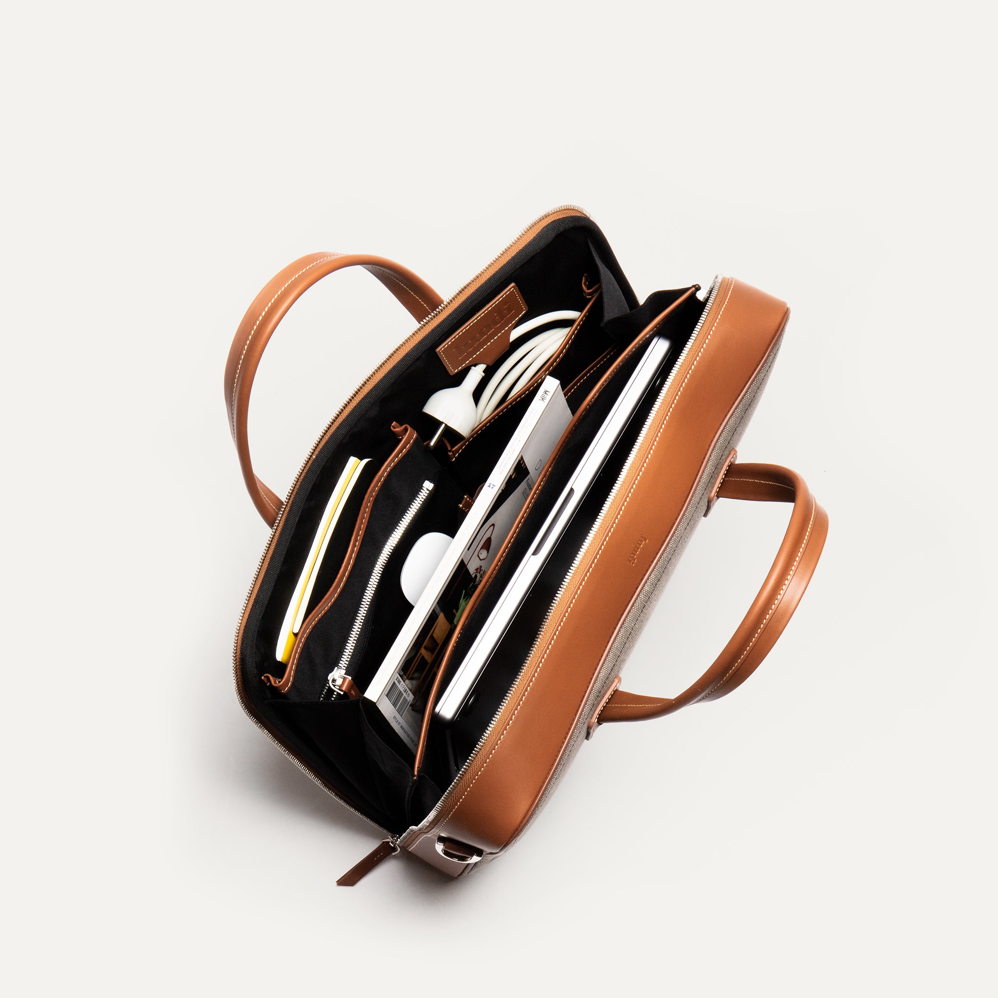 Attaché case en cuir et toile cognac avec des espaces réfléchis pour être pratique.