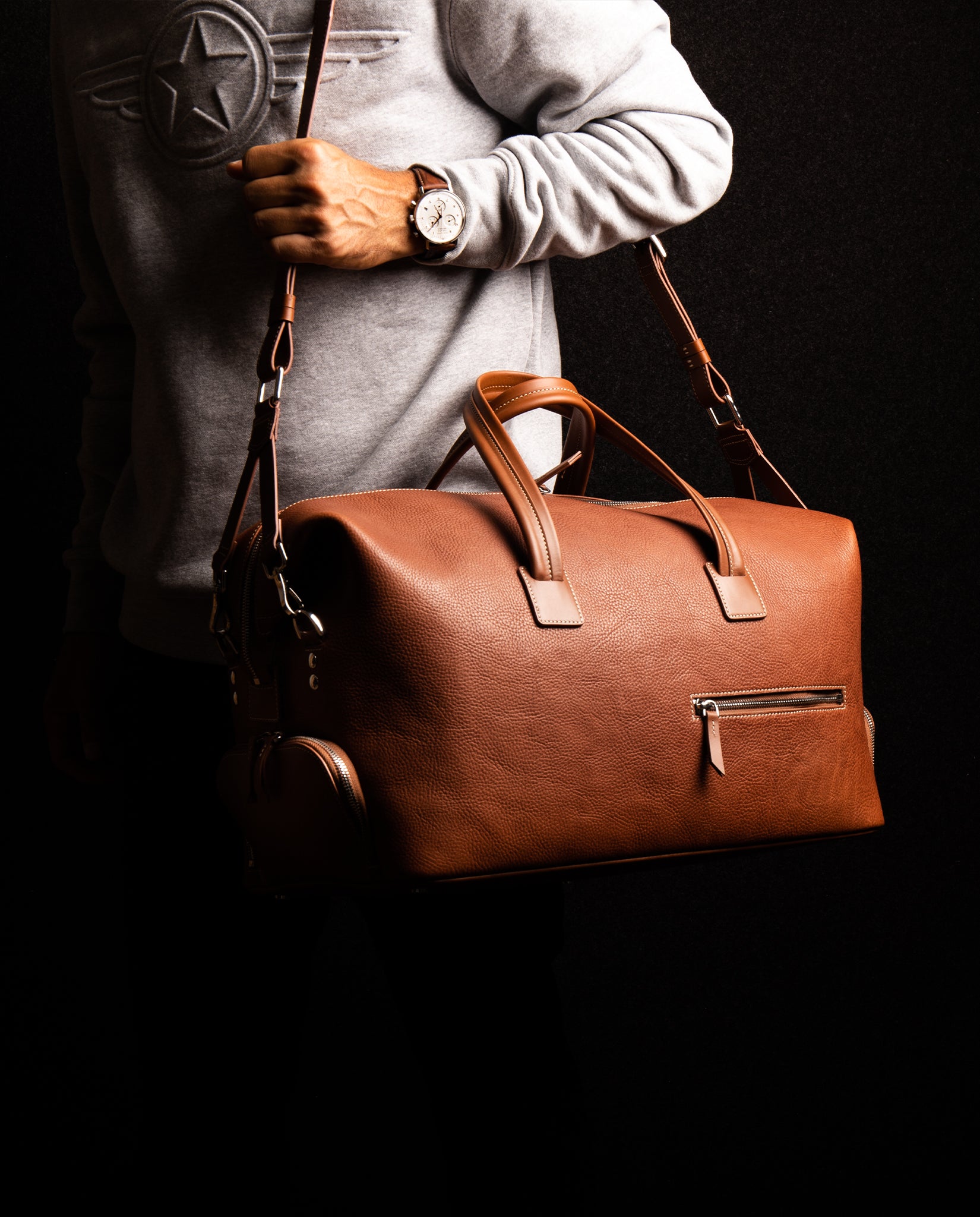 Sac de voyage pour homme en cuir proposé avec une sangle ajustable assorti en cuir cognac.