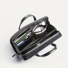 Attaché case lundi ouvert, montrant les multiples rangements pratiques pour ordinateur portable, câbles, carnet et accessoires.