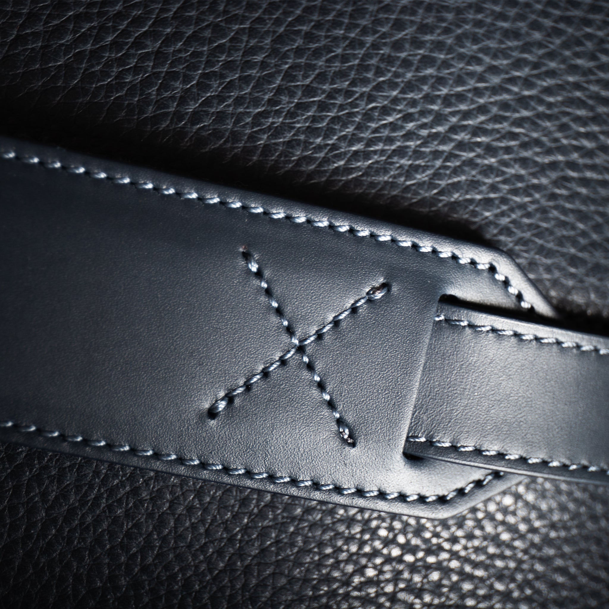 Sac de voyage en cuir marine est équipé de poignées pour un port à la main et d'une sangle en cuir réglable pour un port à l'épaule.