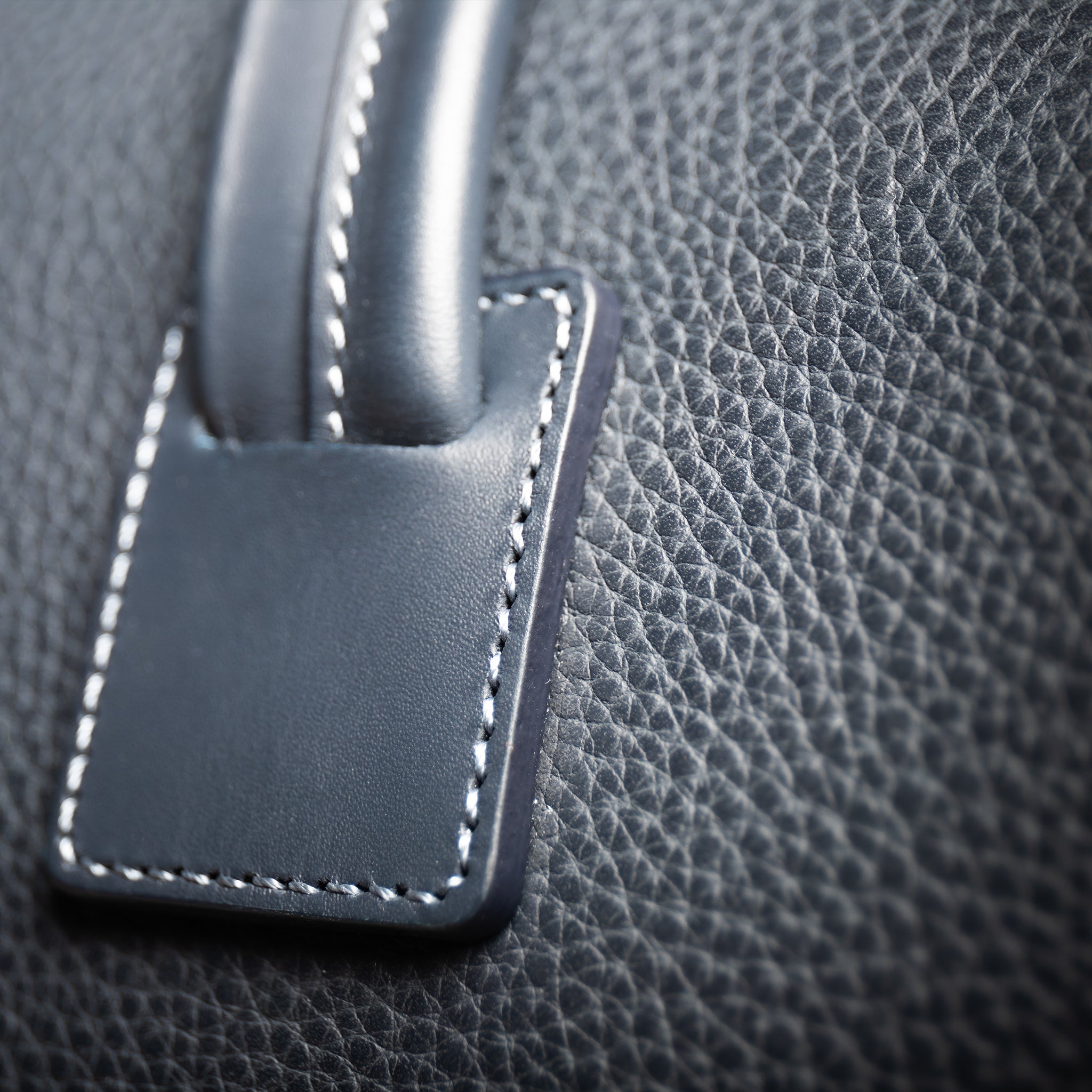 Sac de voyage lundi composé de cuir grainé sur la plupart du sac et de cuir lisse sur les anses et les poches extérieures.