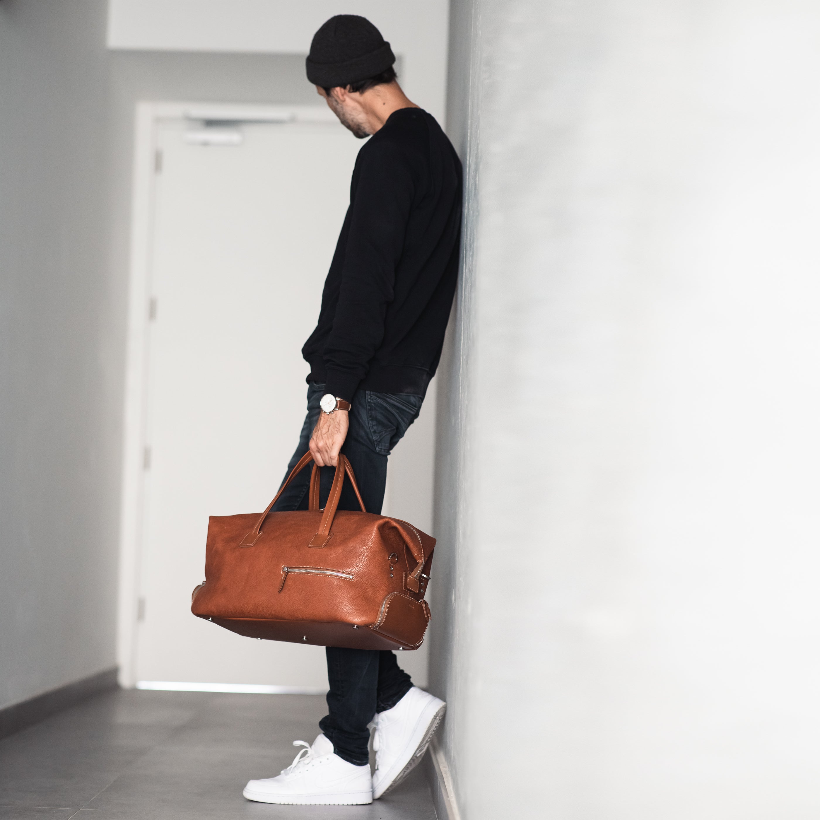 Sac de voyage pour homme en cuir cognac WILSON luxueux tenu par un homme chic.
